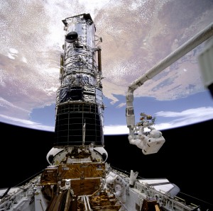 Astronaut in mechanical arm attached to Endeavour works on Hubble